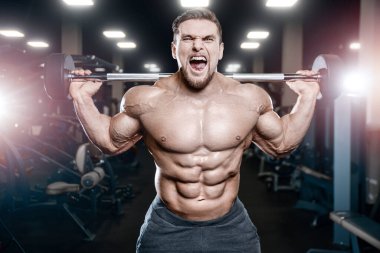 Adam bacak kaslarını şişiriyor vücut geliştirme konsepti spor salonu arka plan egzersizleri spor salonunda çıplak gövde.
