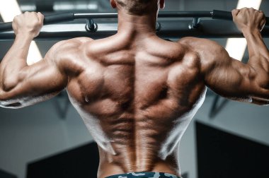 Kas geliştirici fitness erkekler spor salonunda çıplak olarak barfiks egzersizi yapıyor. Yakışıklı, güçlü atletik erkekler sırt kaslarını şişiriyor spor yapıyor ve vücut geliştirme konseptini geri planda tutuyor.