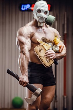 Baltalı vücut geliştirici sporcu, spor salonunda gaz maskeli yemek. Peynirli yumurta ve mısır gevreğiyle kaslı adam Coronavirüs salgını covid-19 pandemik kaos medikal maske kıyamet sonrası vücut geliştirme.