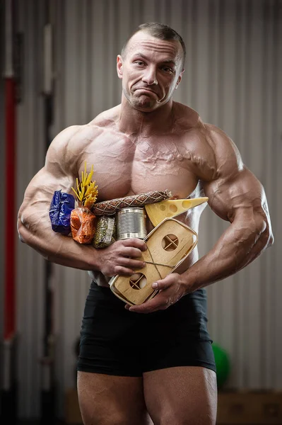 Bodybuilder athlete with axe, food in gas mask in gym. Muscle man with cheese eggs and cereals coronavirus epidemic covid-19 pandemic chaos medical mask post-apocalypse fitness delivery bodybuilding