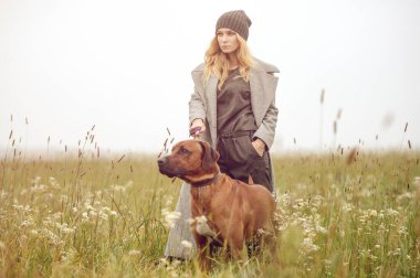 Güzel giyimli, güzel, beyaz, sarı saçlı, şık elbiseli, açık havada köpekli genç kız kırsal alanda bahar veya sonbahar havası depresif.