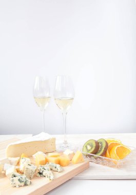Beyaz şarap ve şarap bardakları, peynir ve meyveler hafif arka planda