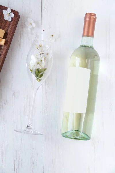 Ahşap arka planda bir şişe şarap, peynir ve şarap kadehi. Dikey fotoğraf