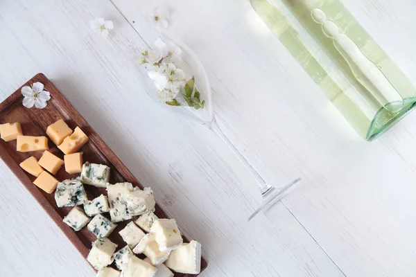 Beyaz ahşap bir arka planda çiçekler ve peynir tabağı.