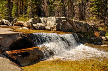 Dağlarda kayalık bir çıkıntının üzerinden akan dere
