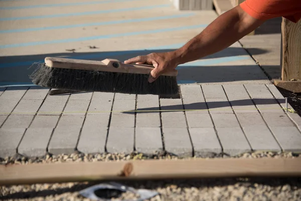 Рабочий убирает бетонный кирпич после укладки — стоковое фото