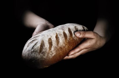 Bir fırıncı siyah bir zemin üzerine elinde taze pişmiş ekmek.