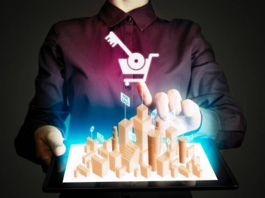 Kadın bir tablet pc onun elinde tutar. Tablet pc ile Emlak Satılık gerçek bir hologram vardır. Online Emlak kavramı.