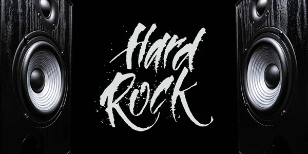 Two sound speakers with hand-drawn words HARD ROCK between them on black background.