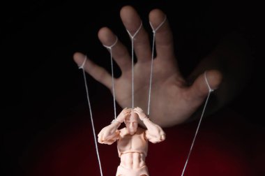Concept of control. Marionette in human hand. Objects are colored on red and blue light. clipart