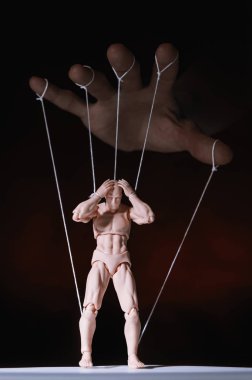 Concept of control. Marionette in human hand. Objects are colored on red and blue light. clipart