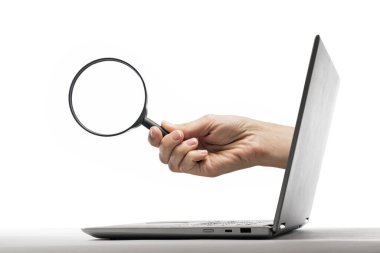 The human hand with magnifier stick out of a laptop screen on a white background.