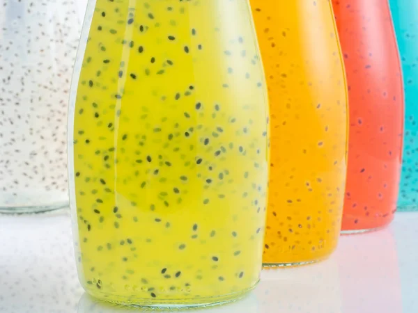 Close up view of bottles of Basil Seed beverage. Red, yellow, light blue and green color. Soft focus. — Stock Photo, Image