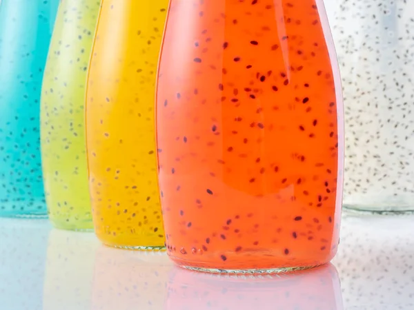 Close up view of bottles of Basil Seed beverage. Red, yellow, light blue and green color. Soft focus. — Stock Photo, Image