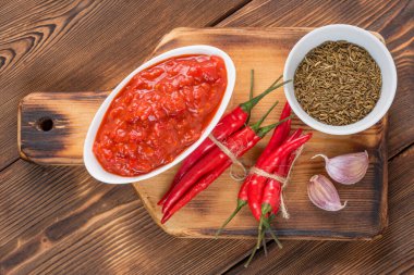 Harissa sos teknesinin en üst görüntüsü. Yanında acı biber, sarımsak ve kimyon tohumları beyaz keten havluyla.