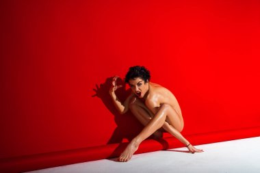 Kusursuz bir beden gölgeni kırmızı ve gri arka plan üzerinde izole kırmızı ipek kumaş ile dans ile güzel çıplak kadın
