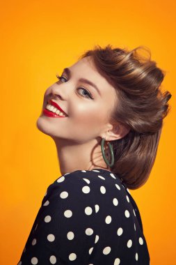 Benekli elbiseli genç kadınların bakış turuncu zemin üzerine kapatın