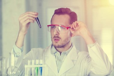 Bilim adamı test tüpüne bakıyor.