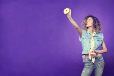 Kıvırcık kız mor zemin üzerine iki donut ile poz