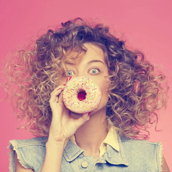 Ung kvinna sätta ansikte till donut — Stockfoto