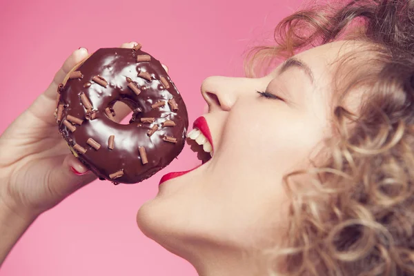 young woman put face to donut