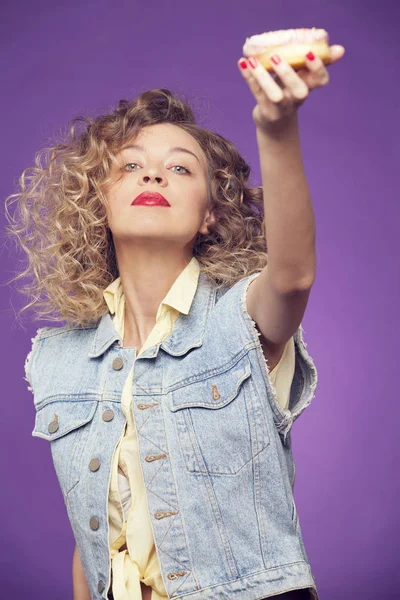 Kıvırcık kız mor zemin üzerine çörek ile poz