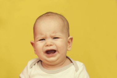 Tombul küçük bebek sarı zemin üzerine ağlaması portresi