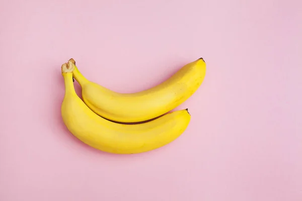 two fresh bananas on a pink background isolated