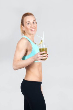 güler yüzlü gri arka plan üzerinde tutan orta yaşlı atletik ince kadın 