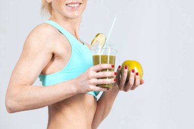 Güler yüzlü ve gülümseyen spor kadının elinde meyve