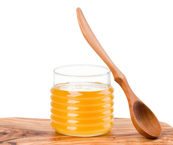 Botol kaca penuh madu dan garpu kayu di papan kayu yang terisolasi di atas putih — Stok Foto