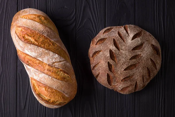 Foto von oben mit frisch gebackenem Brot auf schwarzem Holztisch — Stockfoto