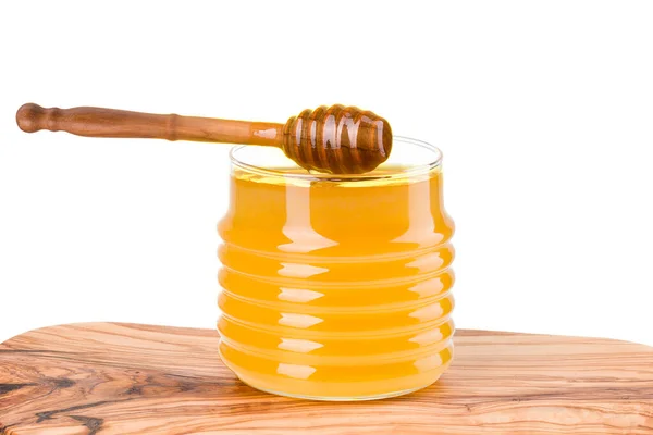 Frasco de vidro cheio de mel e mergulhador de madeira na prancha de madeira isolada no branco — Fotografia de Stock