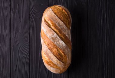 Kurutulmuş taze çavdar ekmeği siyah ahşap bir masada, kırpma yolu ile izole edilmiş.