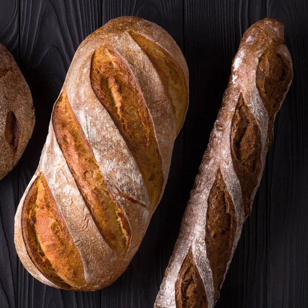 Foto von oben mit frisch gebackenem Brot auf schwarzem Holztisch — Stockfoto