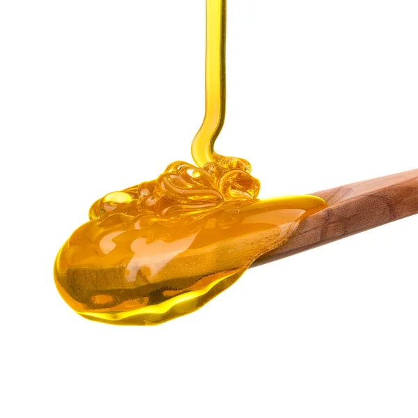 Falling and flowing honey on a wooden spoon isolated on white with clipping path — Stock Photo, Image