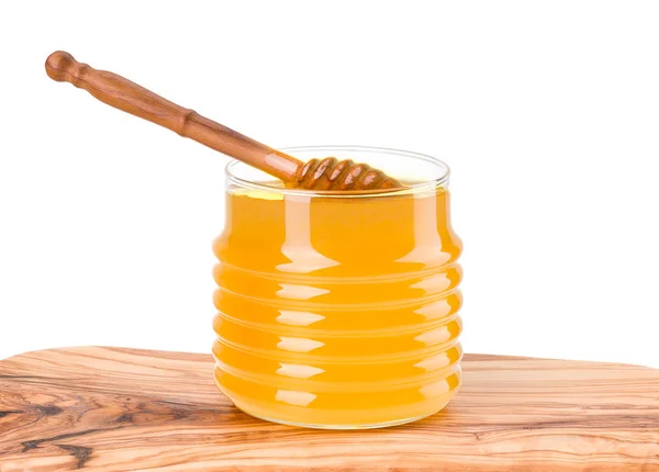 Glazen pot vol honing en houten dipper op houten plank geïsoleerd op wit — Stockfoto