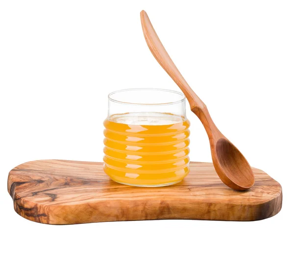 Glazen pot vol honing en houten lepel op houten plank geïsoleerd op wit — Stockfoto