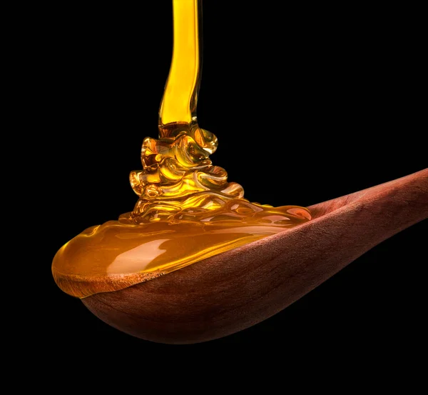Falling and flowing honey on a wooden spoon isolated on black with clipping path — Stock Photo, Image