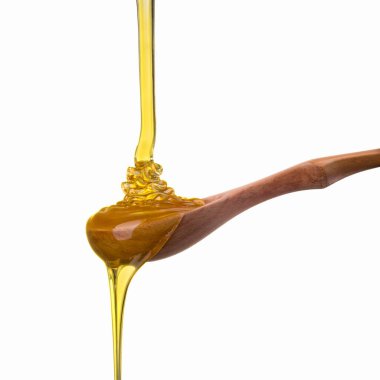 Tahta bir kaşığa düşen ve akan bal beyaz bir kaşık üzerinde kırpma yolu ile izole edilmiş.