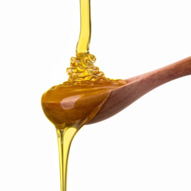 Tahta bir kaşığa düşen ve akan bal beyaz bir kaşık üzerinde kırpma yolu ile izole edilmiş.