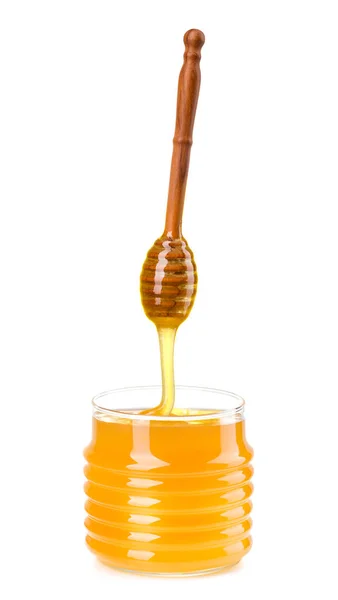 Glass jar full of honey and wooden dipper isolated on white background — 스톡 사진