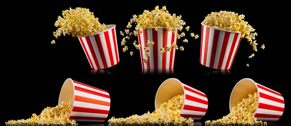 Set di secchi a strisce di carta con popcorn sparsi isolati su sfondo nero — Foto Stock