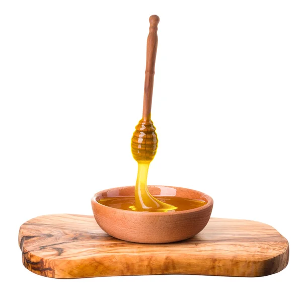 Wooden bowl full of honey and wooden dipper on wooden plank isolated on white — Zdjęcie stockowe