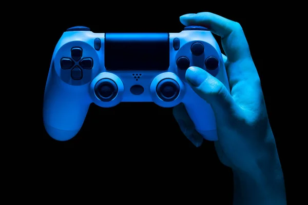 Hyman hand holding white video game gamepad in neon lights isolated on a black — Stock Photo, Image