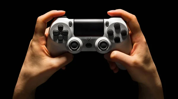 黒の背景に隔離された白いビデオゲームのパッドを保持する人間の手 — ストック写真