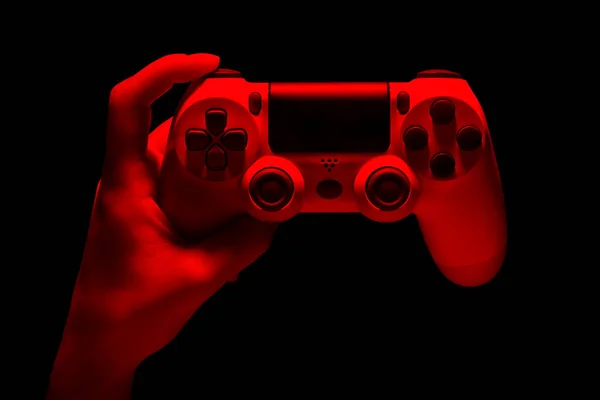 Рука Хаймана держит белый геймпад видеоигры в неоновых огнях, изолированных на чёрном — стоковое фото