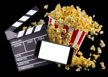 Uçan patlamış mısır, film alkış tahtası ve telefon siyah arka planda izole edilmiş.