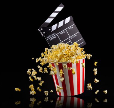 Uçan patlamış mısır ve film alkışları siyah zemin üzerinde izole edilmiş, televizyon veya sinema konsepti.