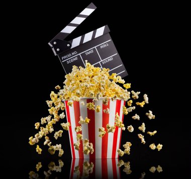Uçan patlamış mısır ve film alkışları siyah zemin üzerinde izole edilmiş, televizyon veya sinema konsepti.